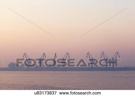 Stock Photo - Cranes at port during sunrise. Fotosearch