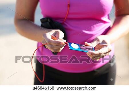 Cropped mid section of mature woman plugging audio jack into mp3 player View Large Photo Image Stock Photo - Cropped mid section of mature woman plugging audio jack into mp3 player. Fotosearch