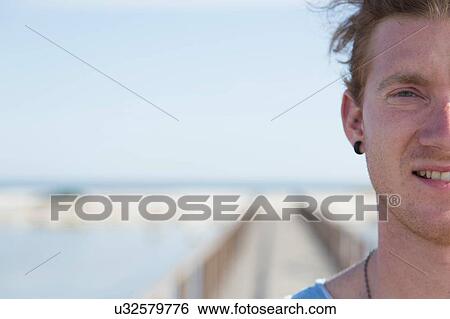 Cropped portrait of young man looking at camera smiling, Sardinia, Italy View Large Photo Image Stock Photograph - Cropped portrait of young man looking at camera smiling, Sardinia, Italy. Fotosearch