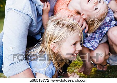 Stock Image - Cropped shot of parents and three young daughters in park. Fotosearch