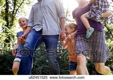 Stock Photography - Cropped shot of parents and three young daughters running in park. Fotosearch