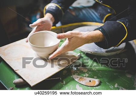Cropped view of mid adult man sitting at potters wheel holding clay pot View Large Photo Image Stock Photography - Cropped view of mid adult man sitting at potters wheel holding clay pot. Fotosearch