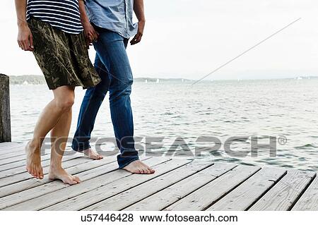 Stock Photo - Cropped view of romantic couple strolling on wooden pier, Lake Starnberg, Bavaria, Germany. Fotosearch