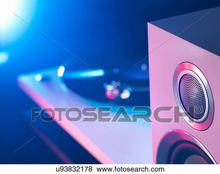 Stock Photo - Detail of purple and blue spot lit hi fi speaker and turntable playing a vinyl record. Fotosearch