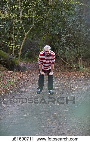 Exhausted mature male runner stopping to catch his breath on forest track View Large Photo Image Stock Image - Exhausted mature male runner stopping to catch his breath on forest track. Fotosearch