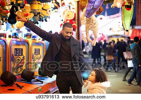 Father at amusement park selecting prize for daughter View Large Photo Image Stock Image - Father at amusement park selecting prize for daughter. Fotosearch