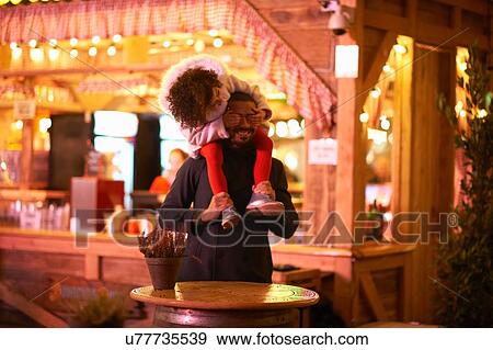 Stock Photo - Father carrying daughter on shoulders, daughter covering father's eyes. Fotosearch