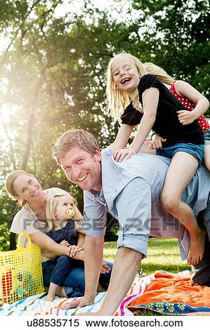 Father giving daughters piggyback at family picnic in park View Large Photo Image Stock Photography - Father giving daughters piggyback at family picnic in park. Fotosearch