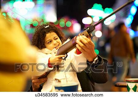 Father helping daughter with rifle at shooting gallery at funfair View Large Photo Image Stock Photography - Father helping daughter with rifle at shooting gallery at funfair. Fotosearch