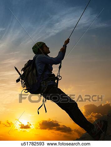 Stock Image - Female climber on rocky wall at sunset, Mont Blanc, France. Fotosearch
