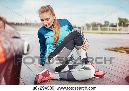 Stock Image - Female runners doing warm up stretches on pier. Fotosearch