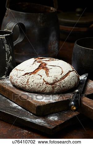 Stock Image - Fresh baked organic bread, Pain de Campagne Rond, on chopping board. Fotosearch