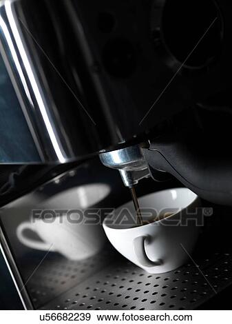 Stock Photo - Fresh coffee pouring into white coffee cup from coffee machine. Fotosearch