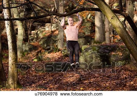 Full length front view of tattooed mid adult man in forest doing pull up on tree View Large Photo Image Stock Photo - Full length front view of tattooed mid adult man in forest doing pull up on tree. Fotosearch