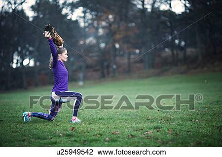 Full length side view of young woman arms raised holding tree branch doing lunge View Large Photo Image Stock Image - Full length side view of young woman arms raised holding tree branch doing lunge. Fotosearch