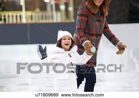 Girl ice skating with mother, holding hands looking at camera smiling View Large Photo Image Stock Photo - Girl ice skating with mother, holding hands looking at camera smiling. Fotosearch