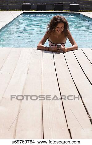 Girl in swimming pool reading smartphone texts, Cassis, Provence, France View Large Photo Image Picture - Girl in swimming pool reading smartphone texts, Cassis, Provence, France. Fotosearch