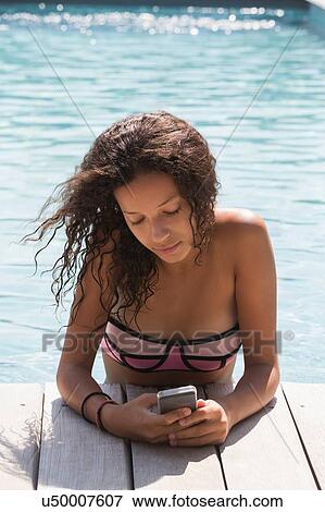 Girl in swimming pool reading smartphone texts View Large Photo Image Stock Photo - Girl in swimming pool reading smartphone texts. Fotosearch