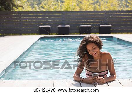 Girl in swimming pool reading smartphone, Cassis, Provence, France View Large Photo Image Stock Photograph - Girl in swimming pool reading smartphone, Cassis, Provence, France. Fotosearch