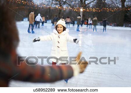 Girl on ice rink, arms open skating to mother smiling View Large Photo Image Stock Photo - Girl on ice rink, arms open skating to mother smiling. Fotosearch