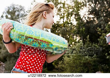 Girl playing with inflatable ring around her neck in park View Large Photo Image Stock Image - Girl playing with inflatable ring around her neck in park. Fotosearch