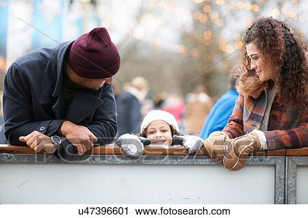 Girl with parents peeking over barrier, looking at camera smiling View Large Photo Image Stock Image - Girl with parents peeking over barrier, looking at camera smiling. Fotosearch