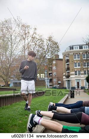Group of adults exercising outdoors, young man holding stopwatch View Large Photo Image Picture - Group of adults exercising outdoors, young man holding stopwatch. Fotosearch
