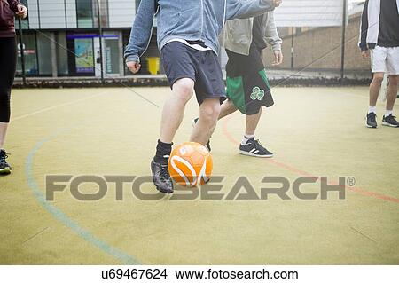 Group of adults playing football on urban football pitch, low section View Large Photo Image Picture - Group of adults playing football on urban football pitch, low section. Fotosearch