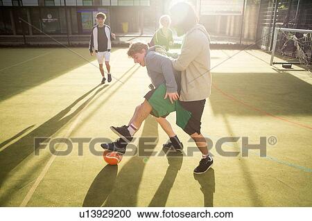 Group of adults playing football on urban football pitch View Large Photo Image Stock Image - Group of adults playing football on urban football pitch. Fotosearch