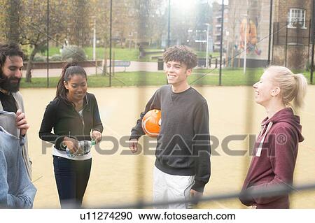 Group of adults standing on urban sports pitch, talking View Large Photo Image Stock Image - Group of adults standing on urban sports pitch, talking. Fotosearch