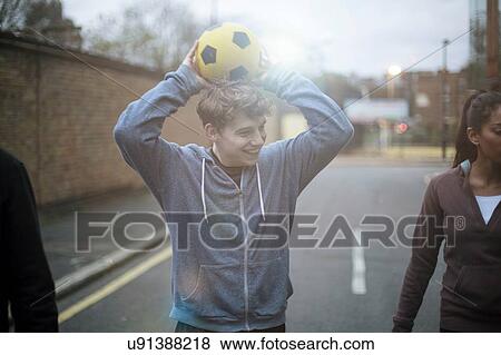 Stock Photo - Group of adults walking street, holding football. Fotosearch