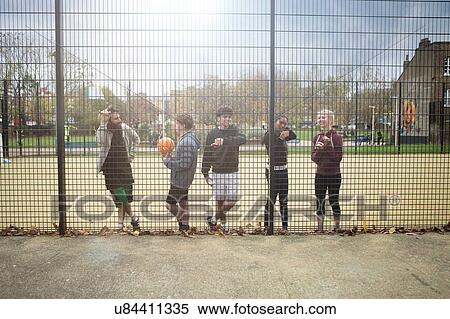 Group of young adults taking break from sport, leaning against fence View Large Photo Image Stock Photography - Group of young adults taking break from sport, leaning against fence. Fotosearch
