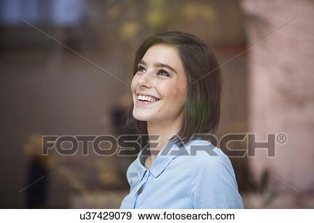 Stock Photo - Happy mid adult woman looking up through window. Fotosearch