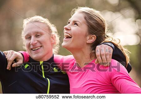 Head and shoulders of couple wearing sports clothing arms around each other looking away smiling View Large Photo Image Stock Image - Head and shoulders of couple wearing sports clothing arms around each other looking away smiling. Fotosearch