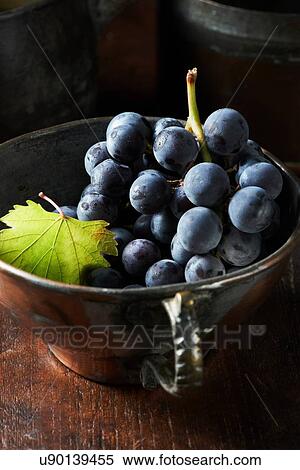 Stock Photography - High angle view of bunch of black grapes in vintage teacup. Fotosearch
