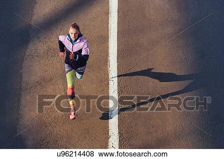 High angle view of female runner running on city road View Large Photo Image Stock Photo - High angle view of female runner running on city road. Fotosearch