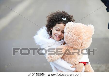 High angle view of girl, eyes closed hugging soft toy View Large Photo Image Picture - High angle view of girl, eyes closed hugging soft toy. Fotosearch