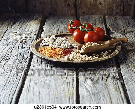 High angle view of red lentils, butter beans, split peas, saffron and vine tomatoes on wooden plate View Large Photo Image Picture - High angle view of red lentils, butter beans, split peas, saffron and vine tomatoes on wooden plate. Fotosearch