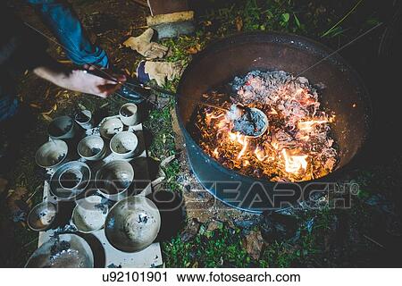 High angle view of young woman using tongs to remove clay pots from fire View Large Photo Image Stock Image - High angle view of young woman using tongs to remove clay pots from fire. Fotosearch