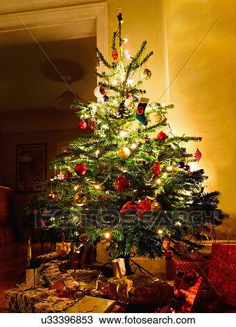 Illuminated christmas tree with gifts underneath View Large Photo Image Stock Image - Illuminated christmas tree with gifts underneath. Fotosearch