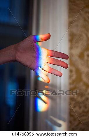 Stock Photography - LIght rainbow reflecting on hand. Fotosearch