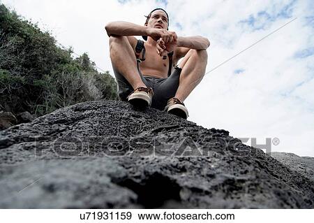 Low angle view of bare chested young man sitting on rocks looking away, Costa Smeralda, Sardinia, Italy View Large Photo Image Stock Photo - Low angle view of bare chested young man sitting on rocks looking away, Costa Smeralda, Sardinia, Italy. Fotosearch