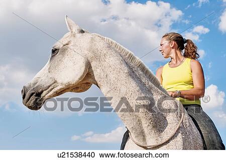 Low angle view of woman riding grey horse bareback against blue sky View Large Photo Image Stock Image - Low angle view of woman riding grey horse bareback against blue sky. Fotosearch