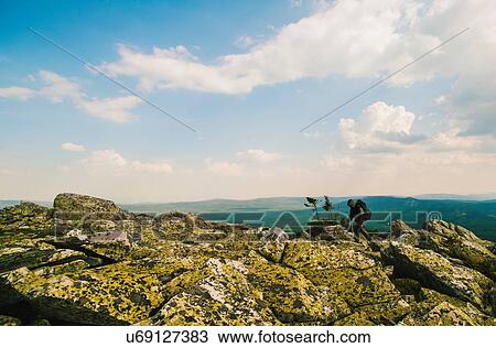 Stock Image - Male hiker hiking on rocks in rugged landscape, Russia. Fotosearch