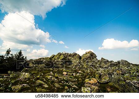 Stock Photography - Male hikers sitting on distant rocks in rugged landscape, Russia. Fotosearch