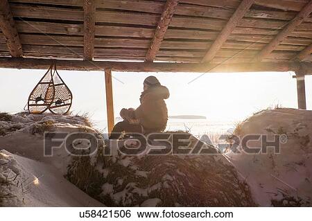 Stock Photograph - Man sitting on snowy haystack in barn with snow shoes, Ural, Russia. Fotosearch