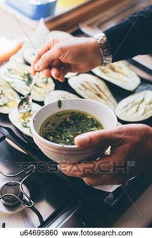 Mans hands drizzling herb oil on aubergine halves in kitchen View Large Photo Image Stock Image - Mans hands drizzling herb oil on aubergine halves in kitchen. Fotosearch