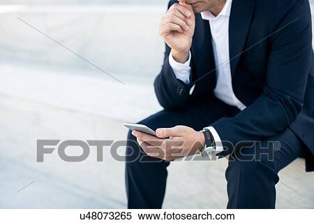 Mature businessman sitting outdoors, using smartphone, mid section View Large Photo Image Stock Photography - Mature businessman sitting outdoors, using smartphone, mid section. Fotosearch