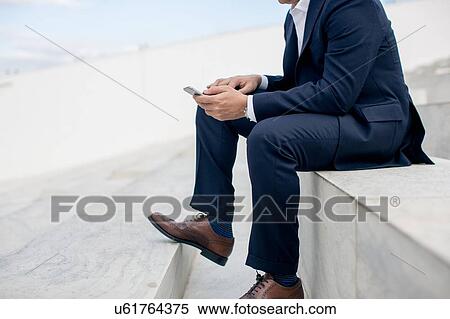 Mature businessman sitting outdoors, using smartphone, low section View Large Photo Image Stock Photography - Mature businessman sitting outdoors, using smartphone, low section. Fotosearch