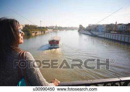 Mature female tourist looking out at Guadalqivir river, Seville, Spain View Large Photo Image Stock Image - Mature female tourist looking out at Guadalqivir river, Seville, Spain. Fotosearch